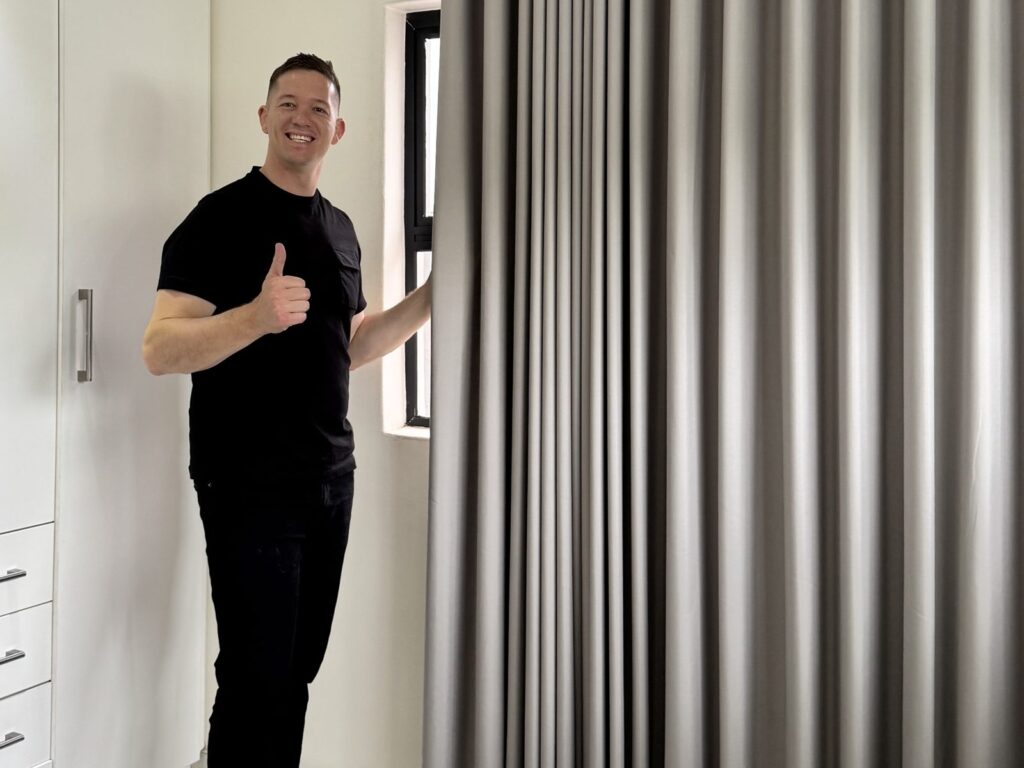 Kyle Van Dalen of Blind Concepts with newly installed blockout wave curtains in a bedroom