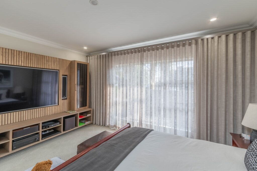 Sheer wave curtains across a bedroom sliding door, made and installed by Blind Concepts